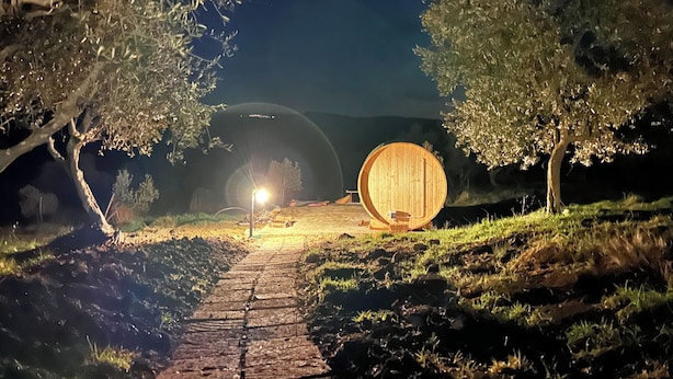 Un sentiero conduce a una struttura di legno a forma di botte, in un'ambientazione notturna.