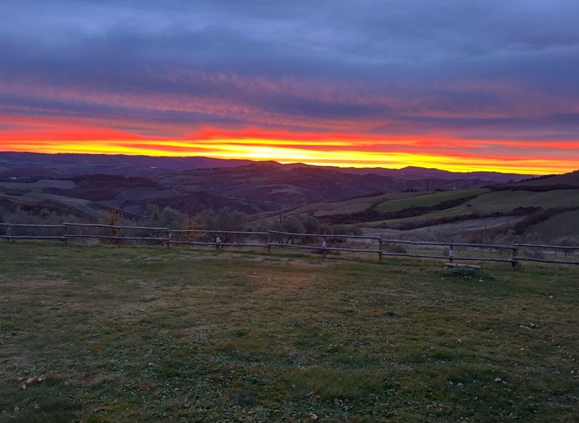 A rural landscape with rolling hills and a fence in the foreground.