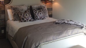 Quarto com cama, ventoinha no teto, obra de arte pendurada e duas luminárias fixadas na parede.
