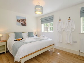 Une chambre à coucher avec un lit, des tables de chevet, une fenêtre donnant sur un beau paysage et un tableau accroché au mur.