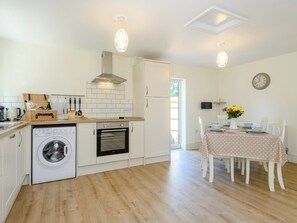 A compact kitchen with a washing machine, oven, and dining area with a table set for two. - 3 bedroom accommodation in Fulletby, near Horncastle (Fulletby, near Horncastle)
