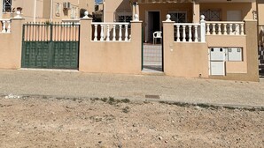 Un edificio residenziale con cancello, un portico coperto e un’antenna parabolica sul tetto.
