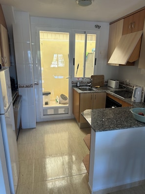 Una cocina con refrigerador, lavamanos y tostadora.