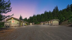 Une rangée de chalets bordée d’une allée de gravier, le tout entouré d’une forêt dense.