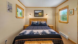 Un dormitorio acogedor con una cama de madera, dos mesitas de noche, un ventilador de techo y una ventana con vistas al exterior.