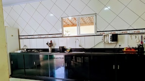 Una cocina con armarios negros, un salpicadero de azulejos y un ventanal con un diseño decorativo.
