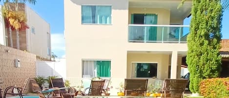 A clear view of a swimming pool area with lounge chairs and a table with a martini glass.