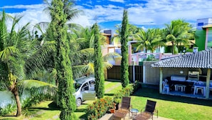 Un patio trasero con piscina, mobiliario exterior y un coche aparcado cerca.