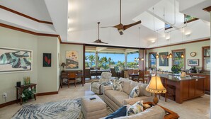 A spacious living area with a large sofa, a dining area with a view, and a kitchen with a bar. - 3 BR penthouse with easy beach access - Hilton Waikoloa Access Included (Waikoloa)