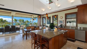 A spacious kitchen with a large island, wooden cabinets, and a view of the ocean. - 3 BR penthouse with easy beach access - Hilton Waikoloa Access Included (Waikoloa)