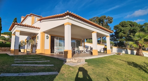 Une maison à deux étages dotée d’un patio couvert, d’un chemin en pierre et d’une pelouse bien entretenue.