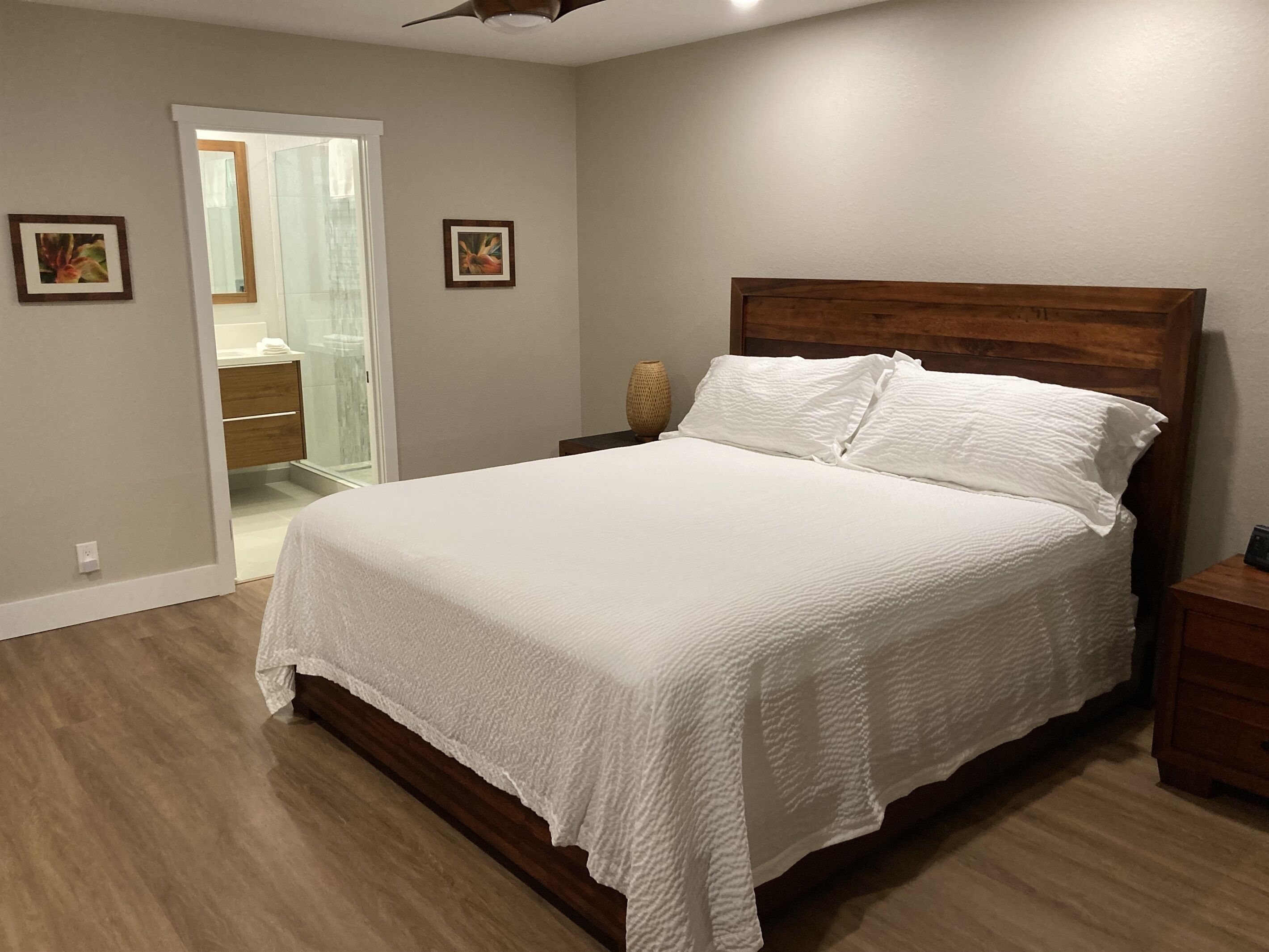Une chambre à coucher avec une tête de lit en bois, du linge de lit blanc et un plancher en bois.