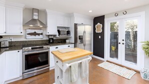 Una cocina moderna con armarios blancos, electrodomésticos de acero inoxidable y encimera de madera.
