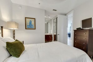 A hotel room with a bed, a dresser, a television, and a framed picture on the wall. - Luxury 12th Floor Condo at Bella Luna (Orange Beach)
