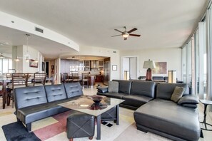 A spacious living area with a sofa, a coffee table, and a dining area in the background. - Luxury 12th Floor Condo at Bella Luna (Orange Beach)