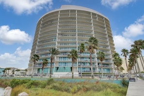 A multi-story hotel with a curved facade, balconies, and a pool area.