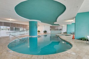 Ein innenliegender, geschwungener Pool, umgeben von einem gefliesten Boden und einer wandfarbenen Türkiswand.