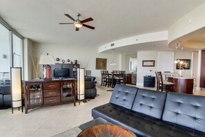 Una sala moderna con un sofá de cuero oscuro, un mueble de entretenimiento de madera y un ventilador de techo.