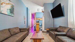 Un salon moderne avec un canapé en cuir marron, une table basse en bois et un téléviseur à écran plat fixé au mur.