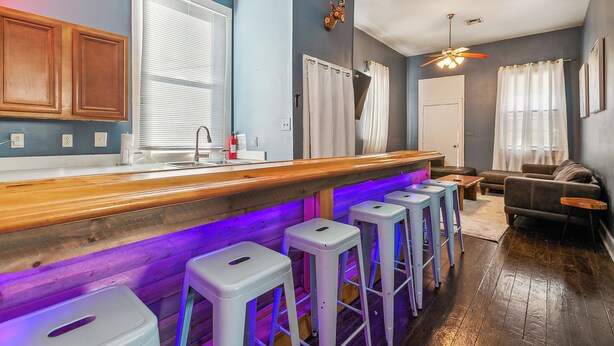 Une cuisine moderne avec des meubles en bois, un coin bar avec des tabourets et un ventilateur de plafond.