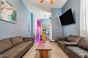 A modern living room with two leather sofas, a wooden coffee table, and a flat-screen TV mounted on the wall.