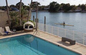 A pool area with lounge chairs, a swing chair, and a view of a body of water. - Spectacular Views, Great Location on Millionaire's Row (Miami Beach)