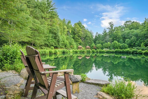 A serene lakeside setting with a wooden chair and gazebo structures.