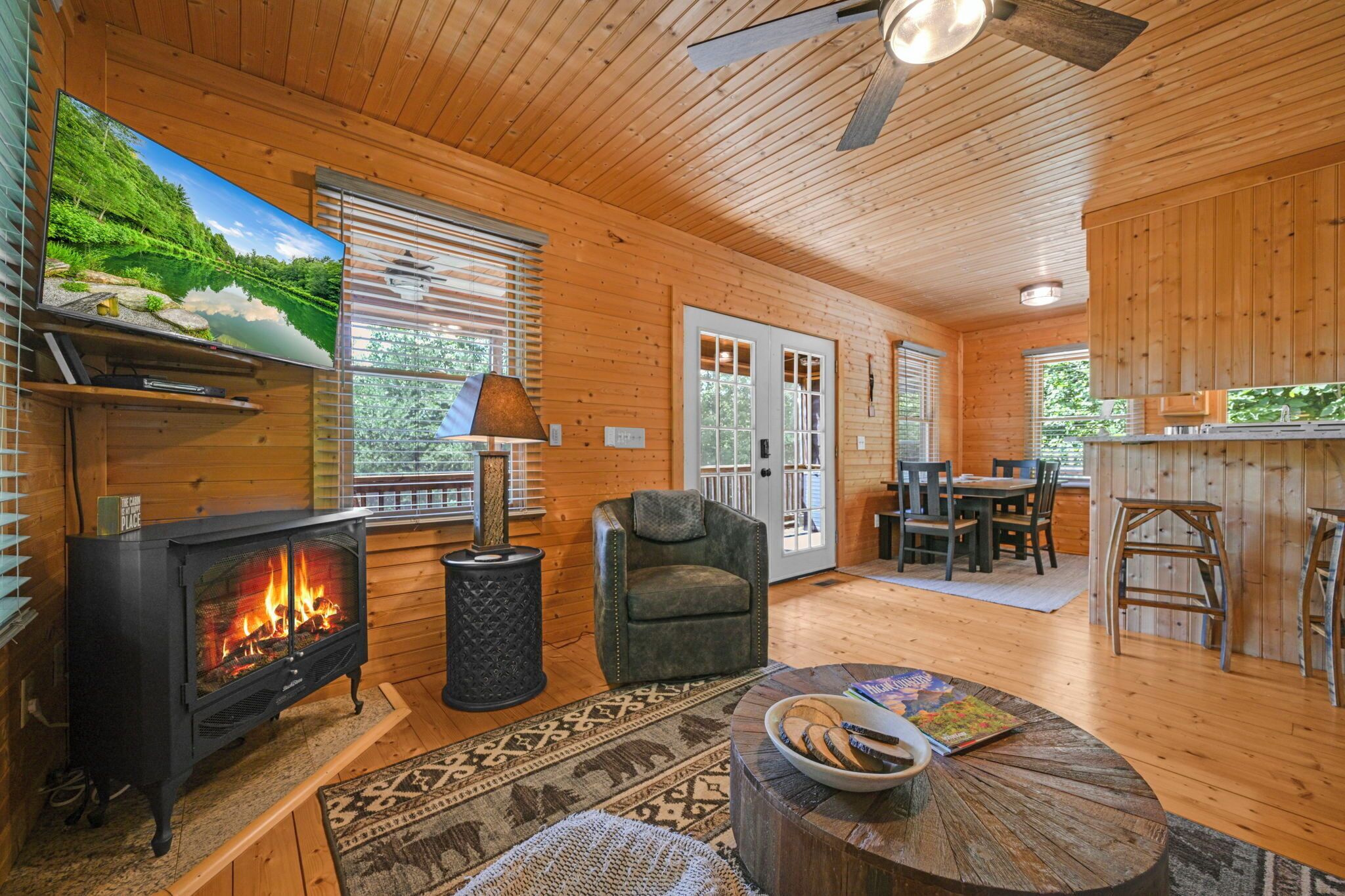 A cozy cabin interior with a fireplace, seating area, and a dining space.