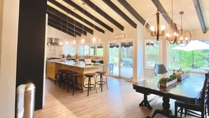 A spacious kitchen with a central island, bar stools, and a dining table with chairs.