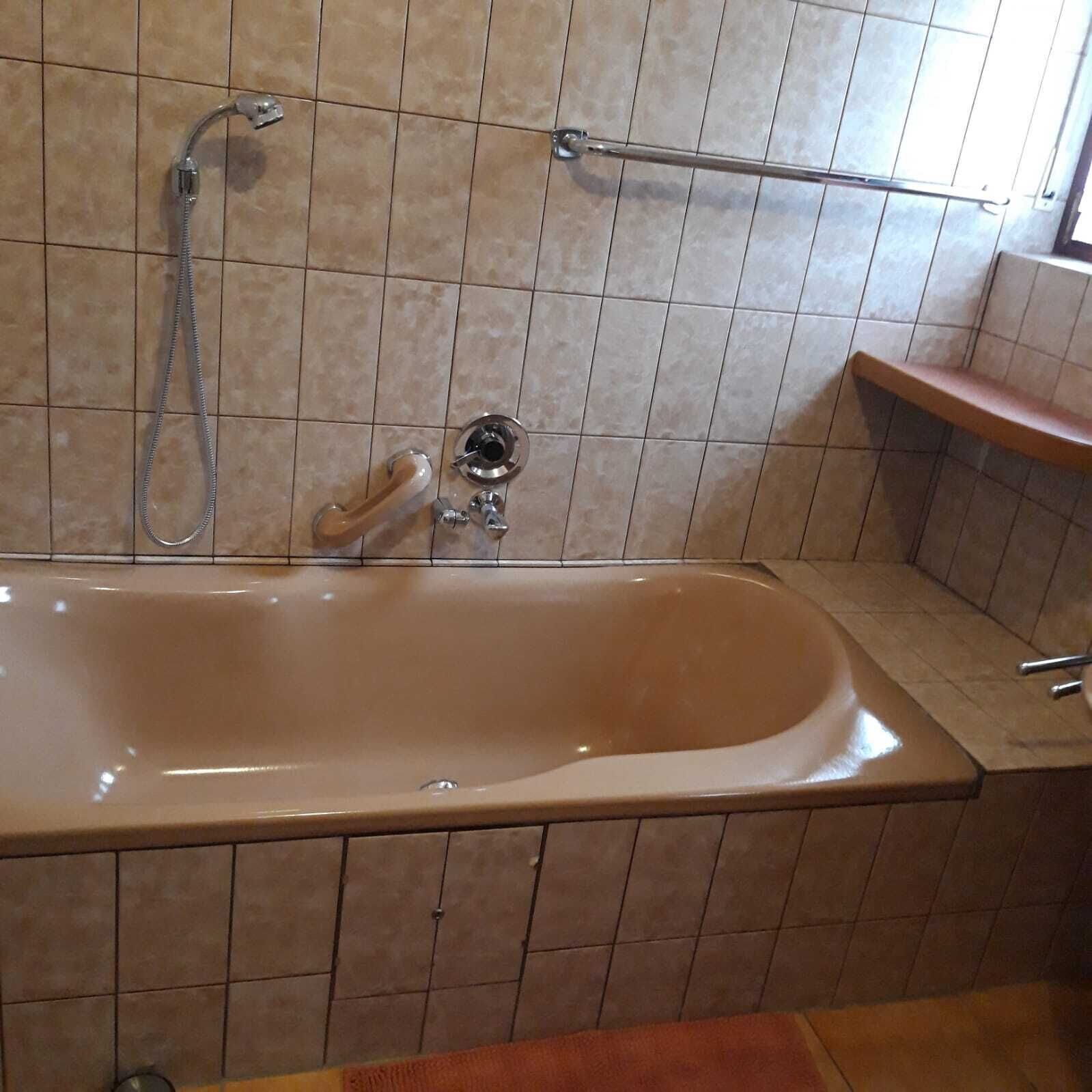 A bathroom with a bathtub, a shower, and a towel rack.
