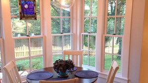 A dining area with a round table, four chairs, and a stained glass window above. - Walk to AVL's TOP restaurants, pubs, etc. Ashehville’s historic Falconhurst area (Asheville)