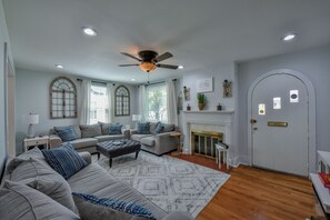 Ein Wohnzimmer mit Deckenventilator, zwei Sofas, einem Couchtisch, einem Kamin und einer Tür.