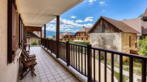 Ein Balkon mit Holzmöbeln und Blick auf traditionelle Gebäude und Berge.