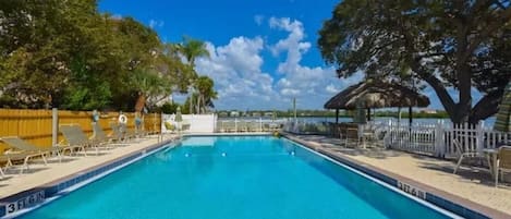 A rectangular swimming pool with a 3 FT 6 IN depth marking, surrounded by a white fence, trees, and lounge chairs.