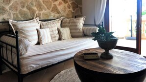 A stone-walled room with a bed, a potted plant, and a small table. - quality furnishings, large pool, stunning sea views, just 200m to the beach (Cala Santanyí)