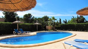 A swimming pool with lounge chairs and thatched umbrellas. - quality furnishings, large pool, stunning sea views, just 200m to the beach (Cala Santanyí)