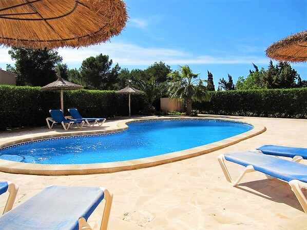 A swimming pool with lounge chairs and thatched umbrellas. - quality furnishings, large pool, stunning sea views, just 200m to the beach (Cala Santanyí)