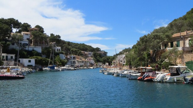 A marina with boats docked, surrounded by buildings and greenery. - quality furnishings, large pool, stunning sea views, just 200m to the beach (Cala Santanyí)