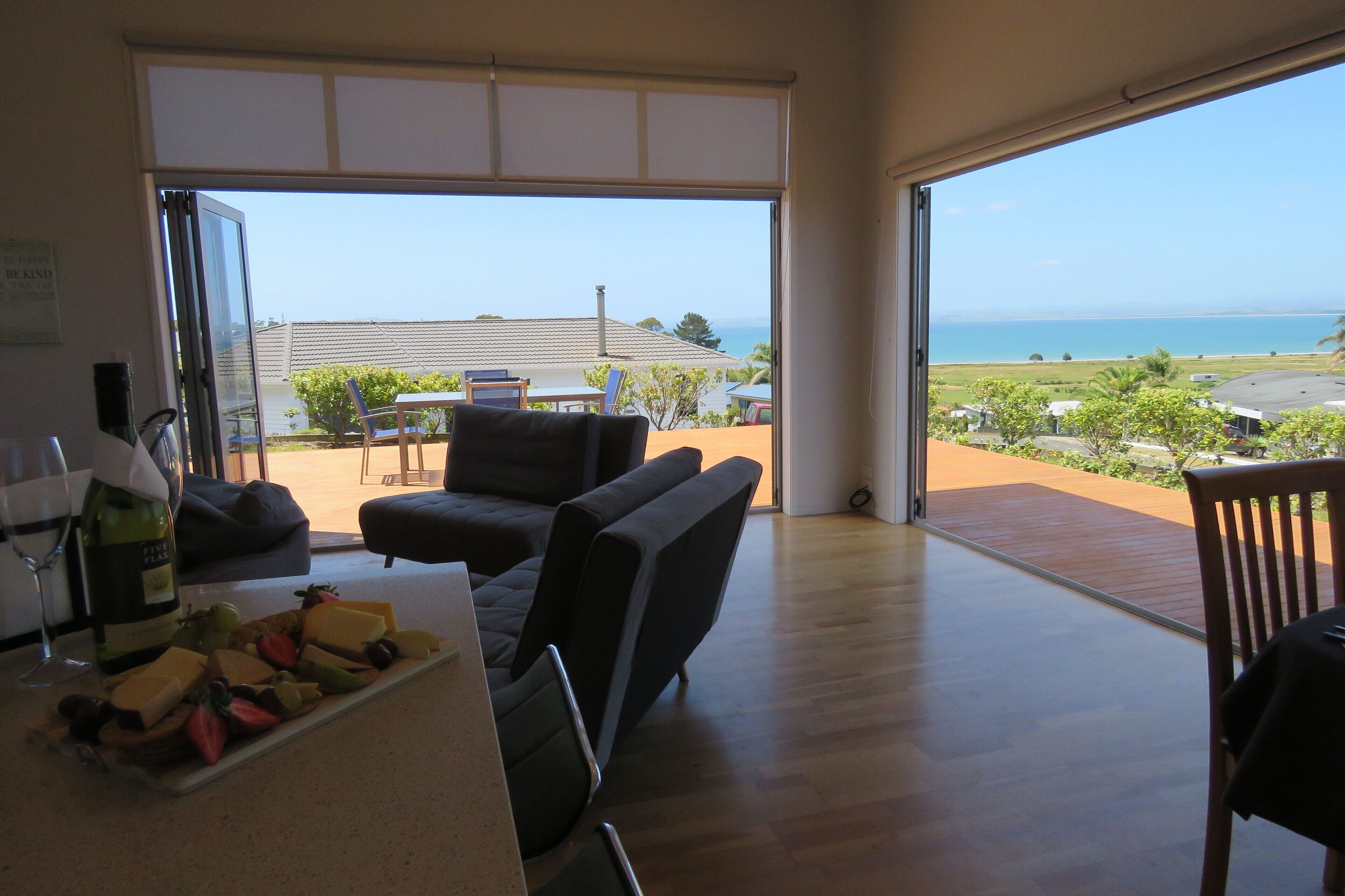 Una habitación amplia con un gran ventanal corredera que da a un balcón con vistas al mar.