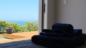A room with a bed, a window with a view of the sea, and a potted plant on the windowsill. - Stunning Views Over Tokerau Beach (Karikari Peninsula)