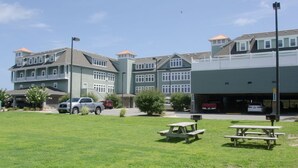 A multi-story building with a parking area and picnic tables in the foreground.