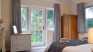 Ein Schlafzimmer mit Bett, Schminktisch, Spiegel und einem Fenster mit Vorhängen.
