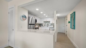 A modern kitchen with white cabinets, stainless steel appliances, and a central island.