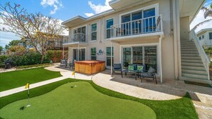 A two-story house with a patio, a hot tub, and a well-maintained lawn.