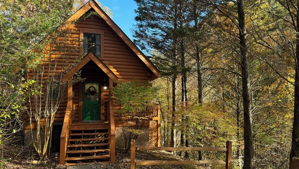 A rustic cabin with a wooden exterior, a porch, and a small entrance. - Cute, Cozy Cabin for a Romantic Getaway! Pool, Putt Putt, Fishing, Golf, Tennis (Sevierville)