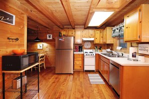Eine kleine Küche mit Holzschränken, einem Kühlschrank, einer Mikrowelle, einem Herd und einem Spülbecken.