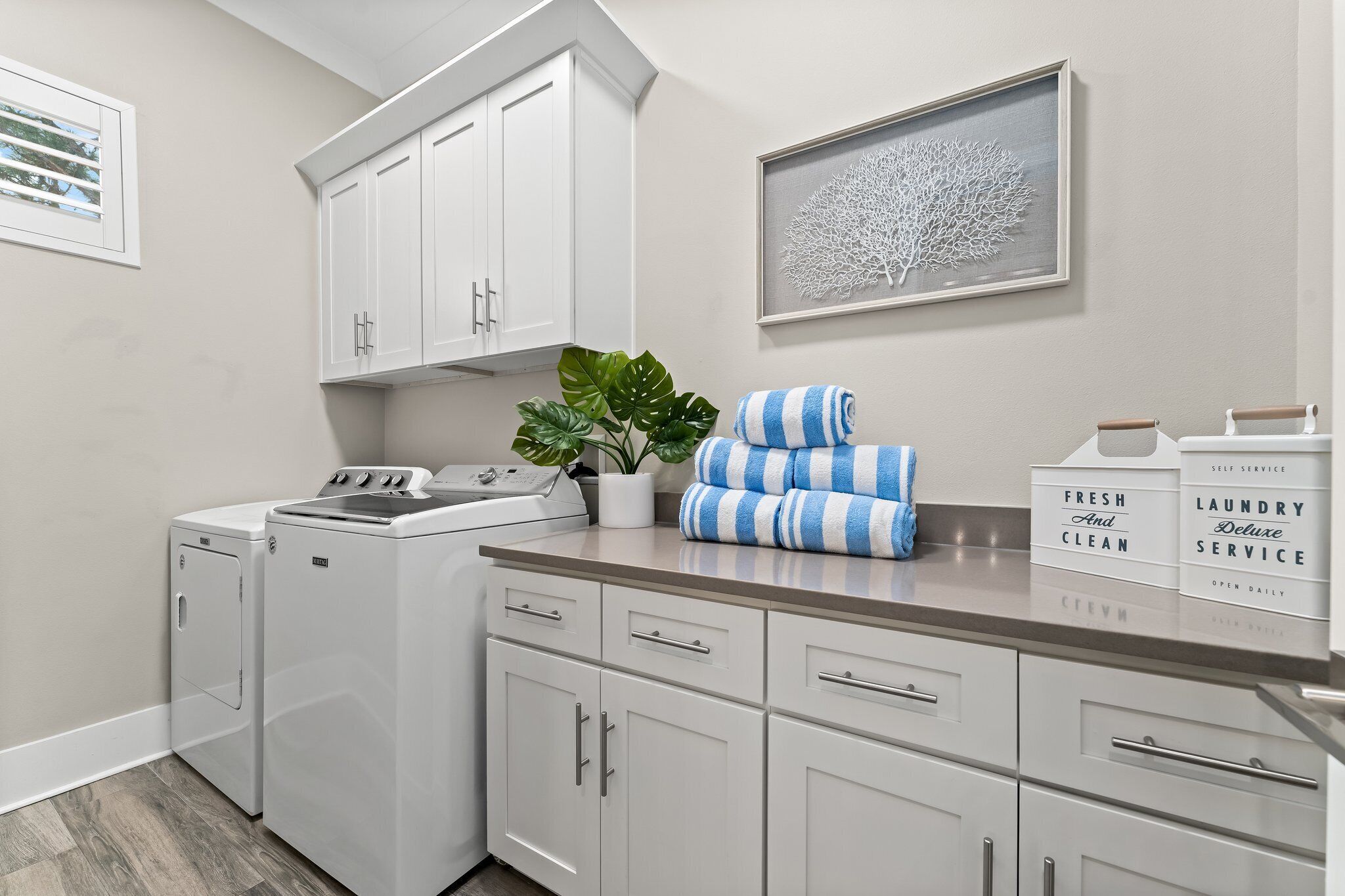 A laundry room with a washing machine, a drying rack, and neatly folded towels.