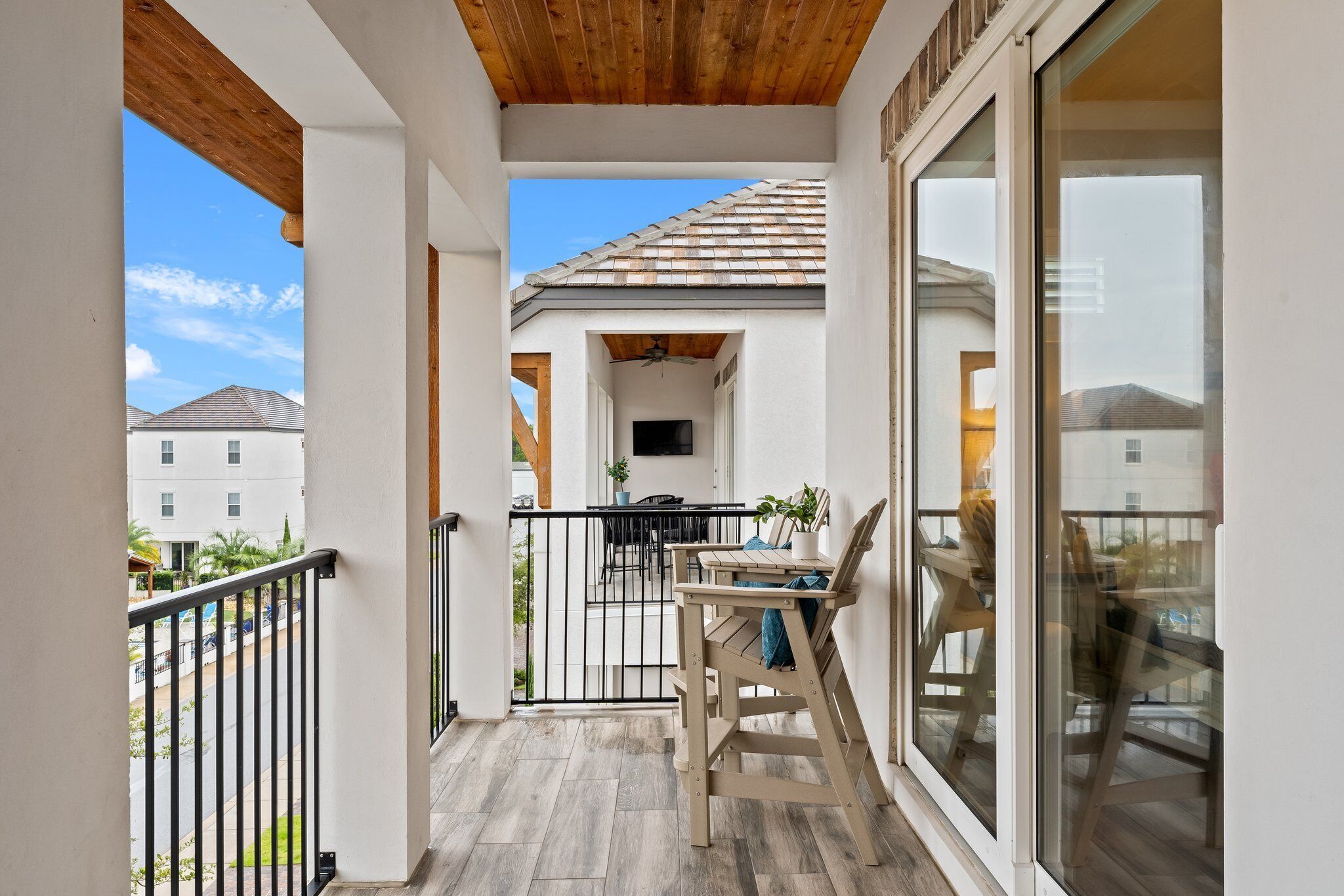 A balcony with a wooden ceiling, a table with chairs, and a view of neighboring buildings.
