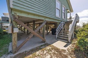 Una casa con terraza de madera, una escalera y un cuadro de empalmes.