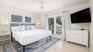 A bedroom with a bed, nightstands, a dresser, a TV, and a balcony door.